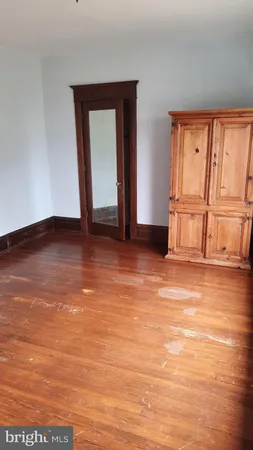 a view of an empty room with wooden floor and window