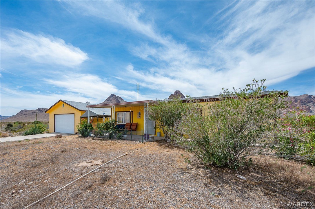 2465 Egar Road Golden Valley, AZ 86413 - Photo 72 of 98 The property features a yellow exterior, a covered porch, and an attached garage with a white door