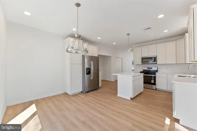 a kitchen with stainless steel appliances granite countertop a refrigerator a stove top oven a sink dishwasher and a refrigerator with wooden floor