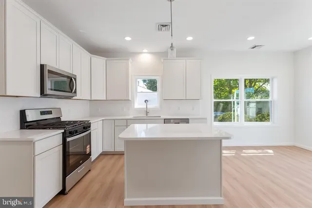 a kitchen with stainless steel appliances granite countertop a sink a stove top oven a counter space and cabinets