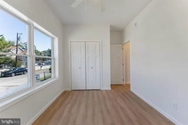 a view of hallway with window and wooden floor