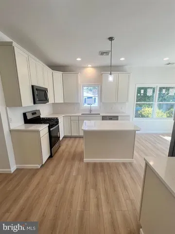 a large kitchen with kitchen island a sink a stove a microwave a center island and cabinets