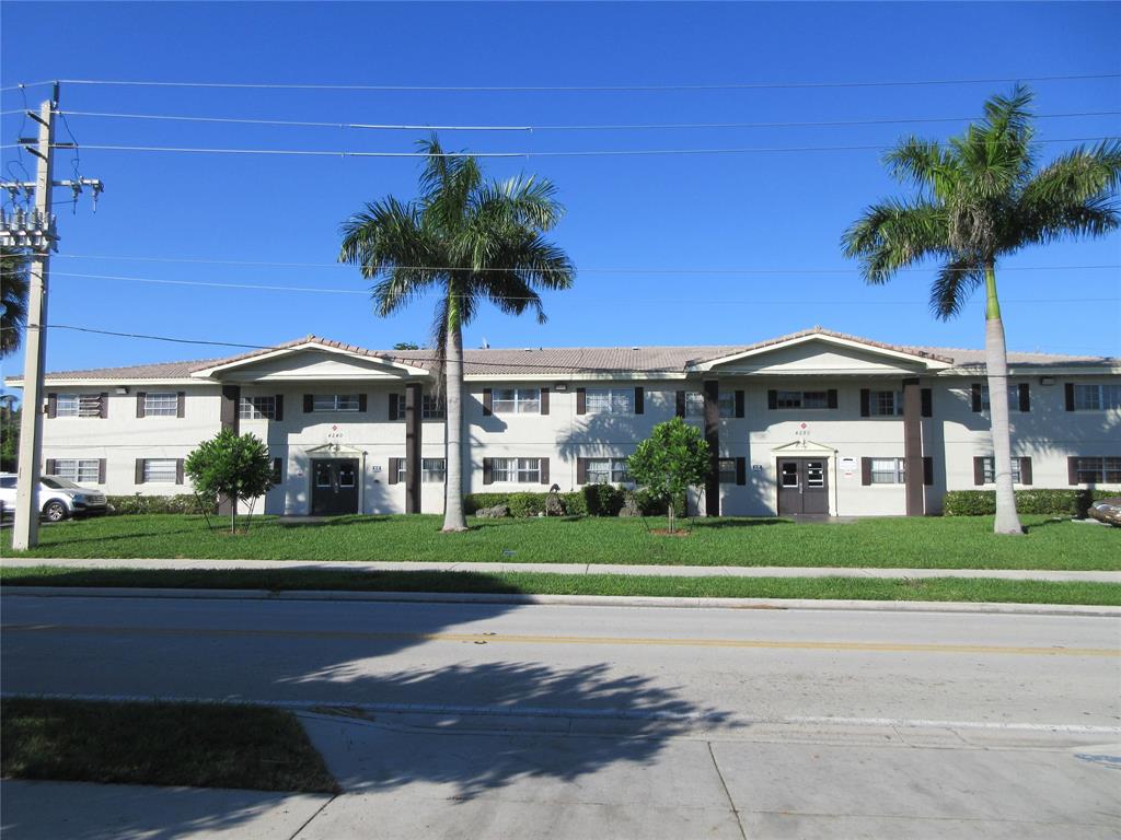 a front view of a house with a yard and palm trees