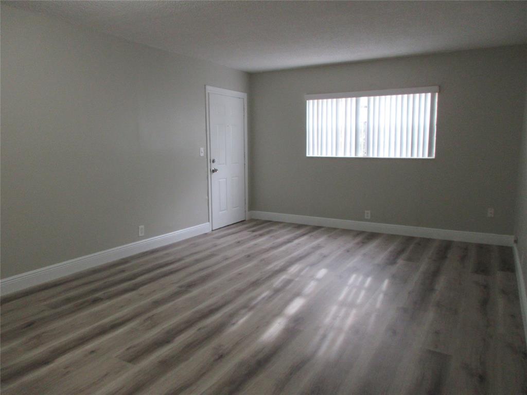 4240 Woodside Drive, Unit 4 Coral Springs, FL 33065 - Photo 5 of 13 a view of an empty room with wooden floor and a window