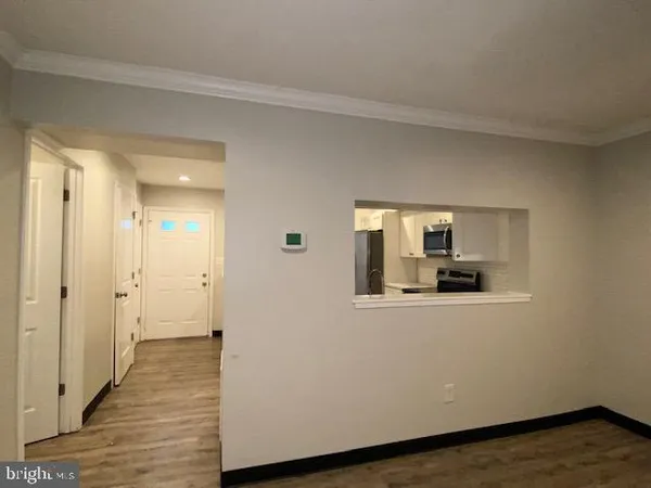 a view of a hallway with wooden floor and a bathroom