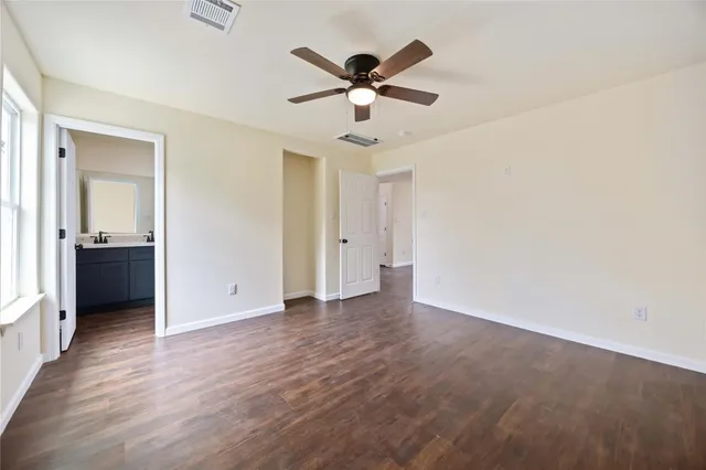 an empty room with wooden floor and ceiling fan