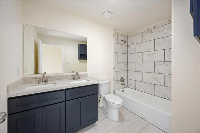 a bathroom with a bathtub shower sink mirror vanity and toilet