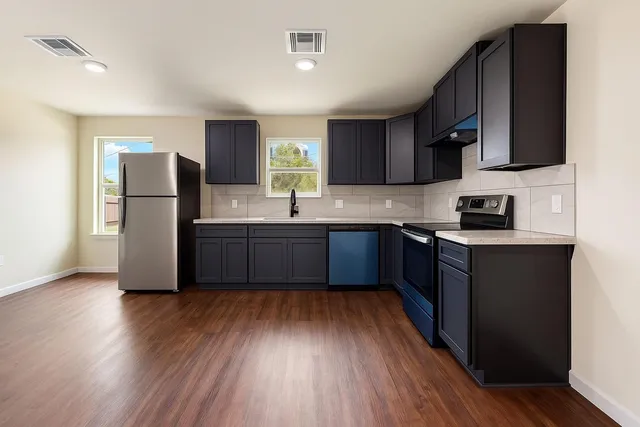 a kitchen with stainless steel appliances granite countertop a refrigerator a sink dishwasher a stove with wooden floor and cabinets