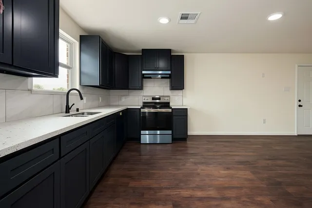 a kitchen with granite countertop a sink and a stove top oven