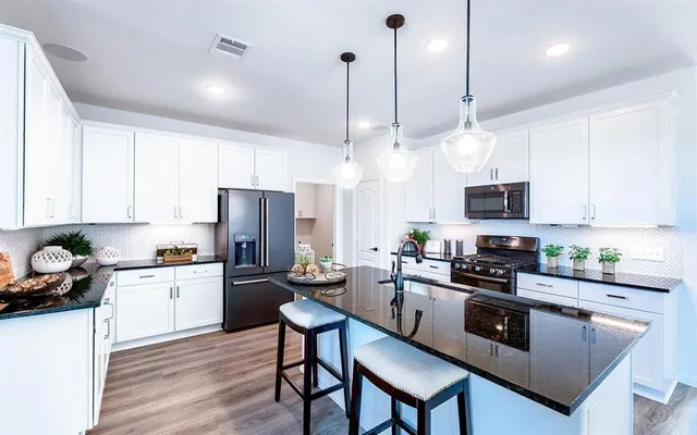 a kitchen with stainless steel appliances kitchen island granite countertop a stove a sink a refrigerator a stove a microwave and wooden cabinets