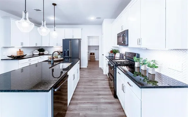 a kitchen with granite countertop a sink a counter space stainless steel appliances and cabinets