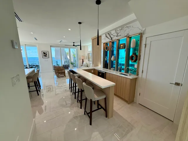 a dining hall with stainless steel appliances kitchen island granite countertop a table chairs and a rug