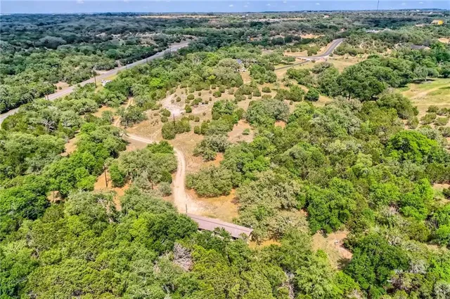 an aerial view of residential houses with outdoor space and trees