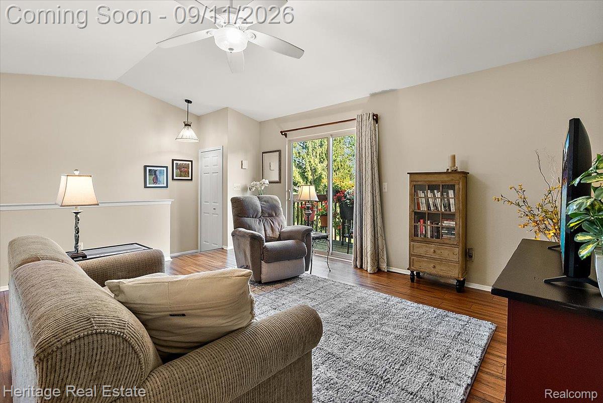 Vaulted ceiling with a ceiling fan, wood-finish flooring, sliding glass door, and neutral wall paint