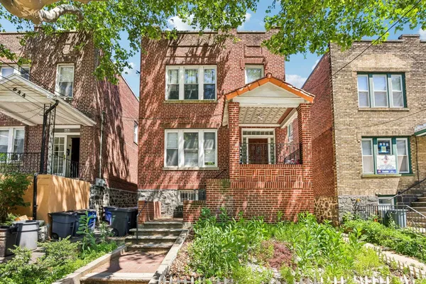 a view of a brick house with many windows next to a yard