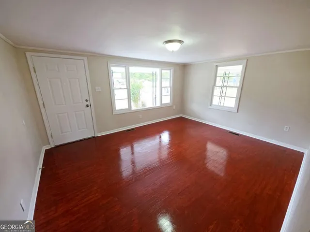 an empty room with wooden floor and windows