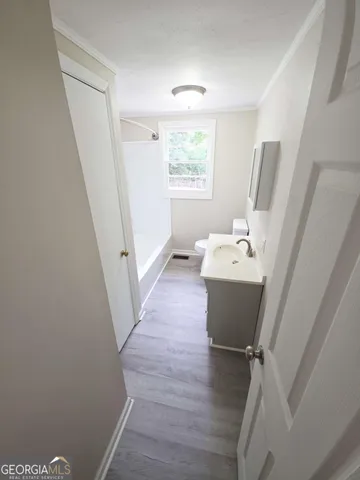 a bathroom with a sink a window and hardwood floor