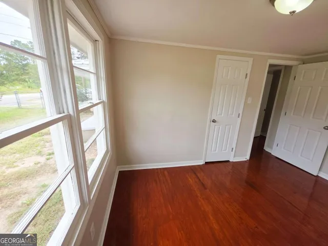 a view of an empty room with wooden floor and a window