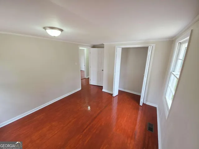 an empty room with wooden floor and closet