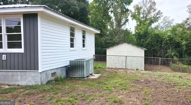 a view of backyard with small cabin and wooden fence