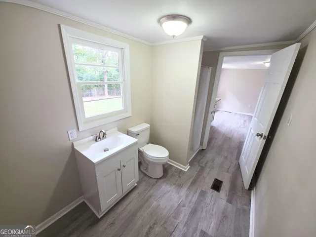 a bathroom with a toilet a sink a mirror and a window