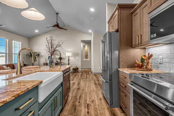 a kitchen with kitchen island granite countertop a sink cabinets and stainless steel appliances