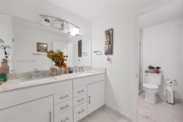 a bathroom with a double vanity sink mirror and toilet