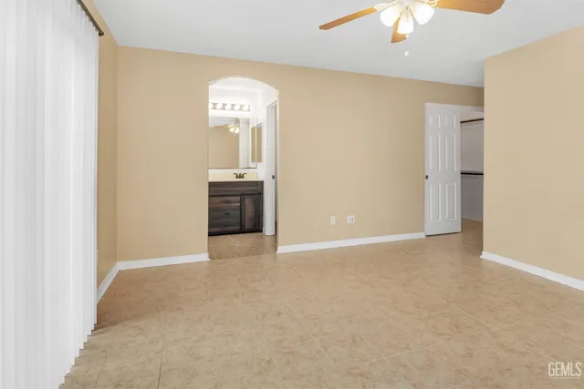 an empty room with a chandelier fan and a window