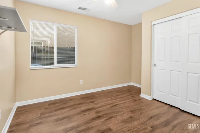 an empty room with wooden floor and windows