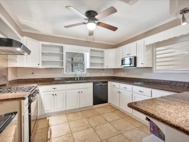 a kitchen with granite countertop cabinets stainless steel appliances a sink and a window
