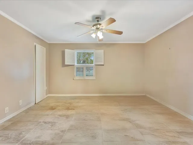 an empty room with window and ceiling fan