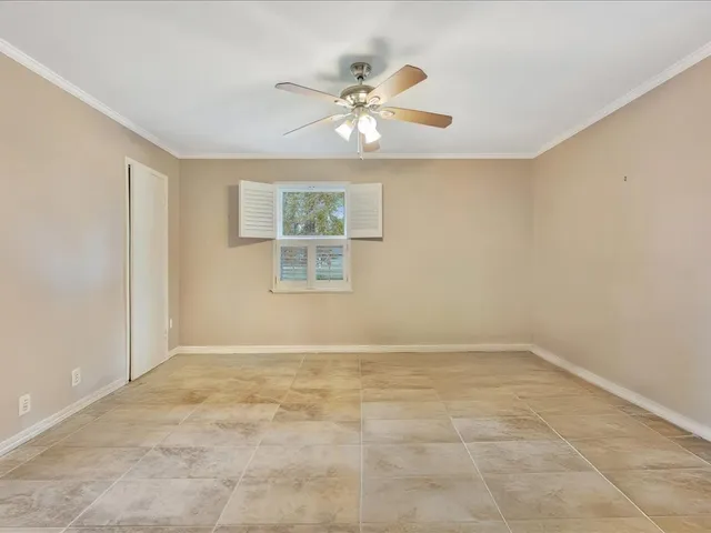 an empty room with window and ceiling fan