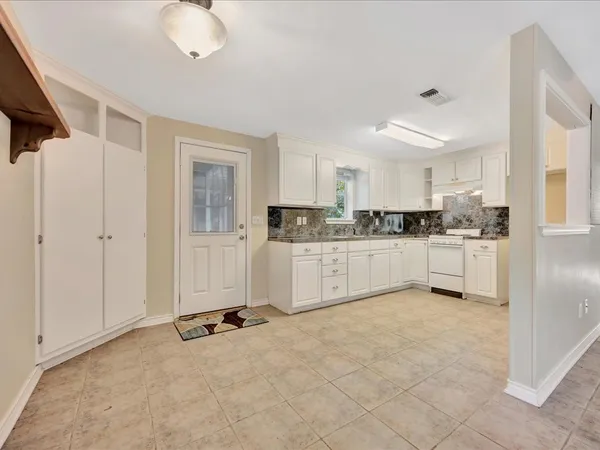 a kitchen with granite countertop a stove a sink and a refrigerator