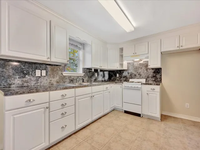 a kitchen with granite countertop white cabinets and white stainless steel appliances
