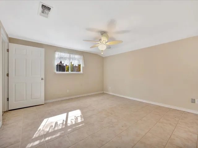 an empty room with windows and fan