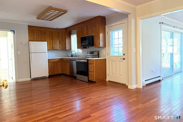 a kitchen with stainless steel appliances granite countertop a refrigerator a stove top oven a sink and dishwasher with wooden floor