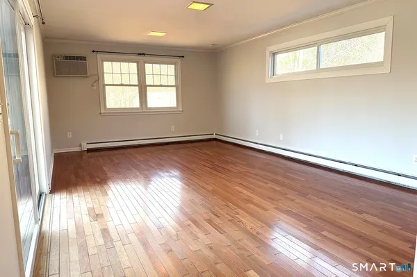 an empty room with wooden floor and windows