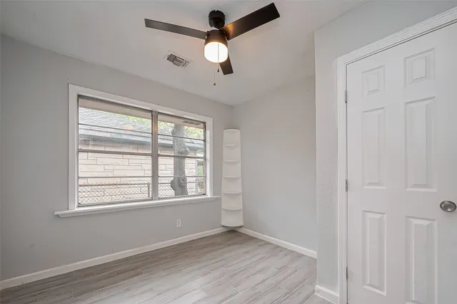 a view of an empty room with a window and wooden floor
