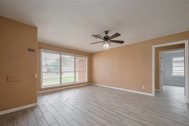 a view of an empty room with a window and wooden floor