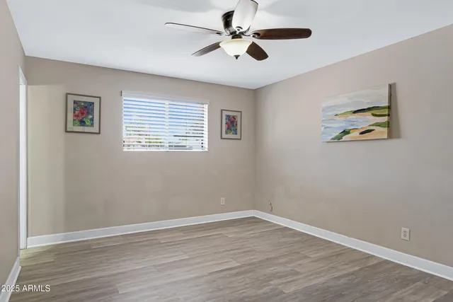 a view of an empty room with a window and wooden floor