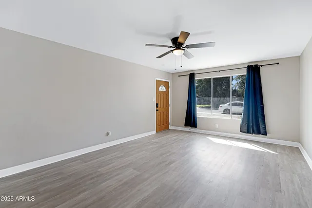 a view of a livingroom with wooden floor and a ceiling fan
