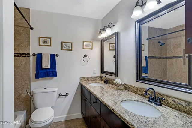 a bathroom with a granite countertop sink toilet and mirror