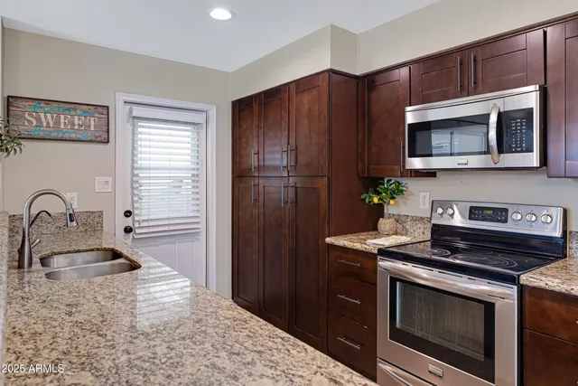 a kitchen with stainless steel appliances granite countertop a sink stove and refrigerator