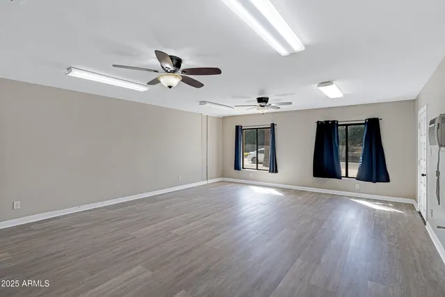 a view of an empty room with window and wooden floor