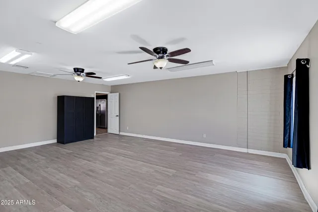 a view of an empty room with a ceiling fan and window