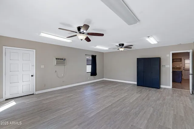 a view of an empty room with wooden floor and a ceiling fan