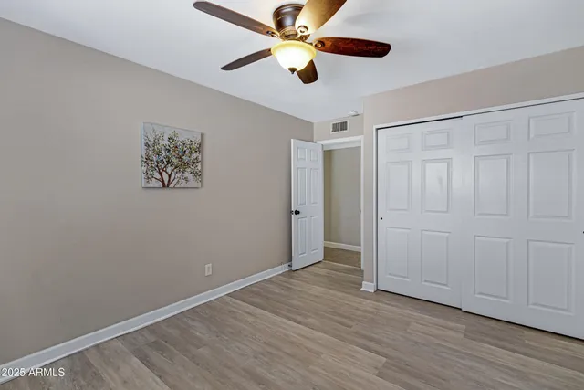 an empty room with wooden floor closet and ceiling fan