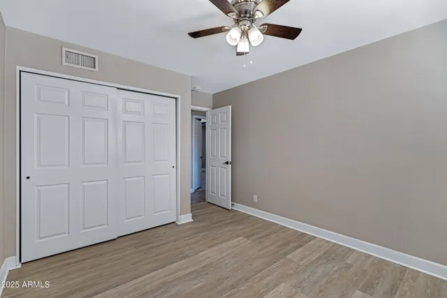 an empty room with wooden floor closet and windows