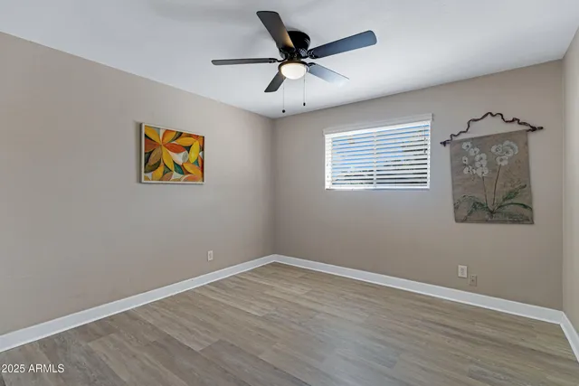 an empty room with wooden floor and ceiling fan