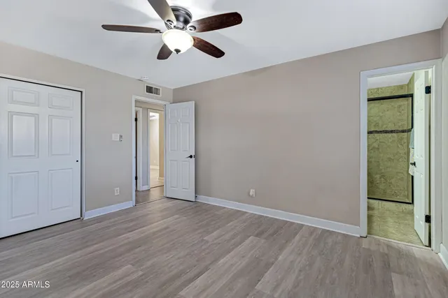 an empty room with wooden floor a ceiling fan and entryway